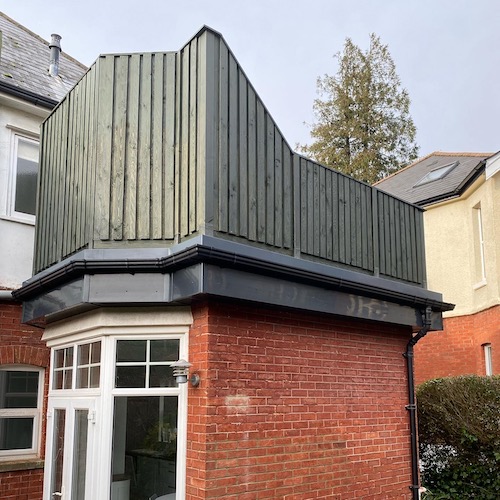 Fence panelling installed on the roof around the decking of an outhouse